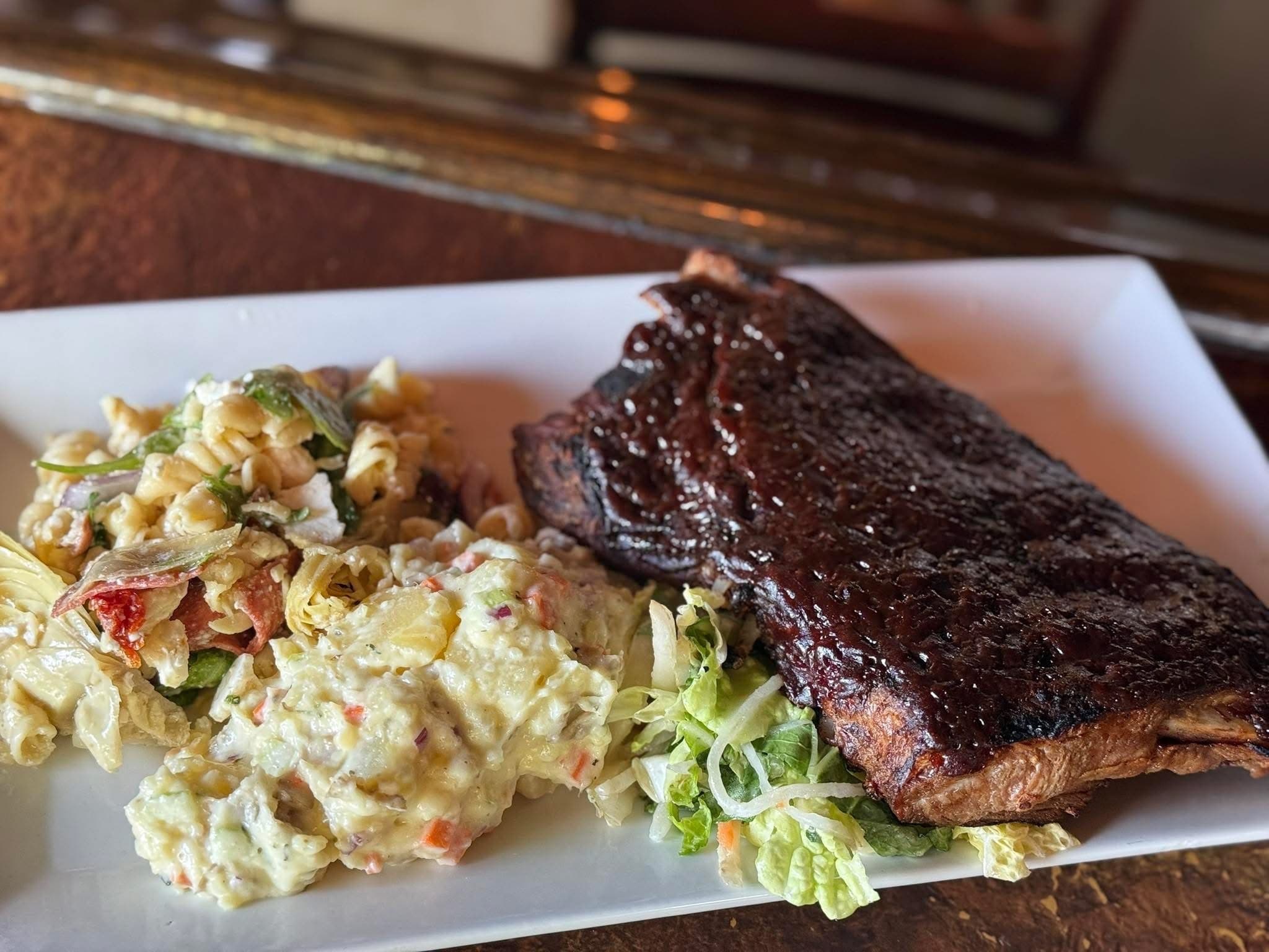 Sous vide spare ribs charbroiled in sweet BBQ sauce, served with potato salad, antipasti salad and shredded vegetable slaw at The Mansard Inn